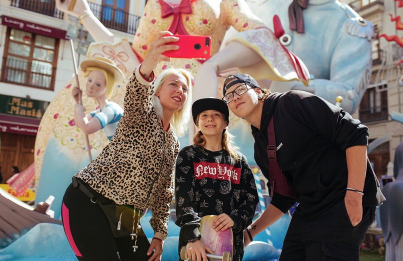 Tres turistas se están haciendo un selfie con un monumento fallero detrás