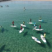 turistas practicando paddle surf en la playa