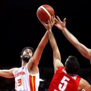 Foto de tres jugadores de baloncesto de las selecciones de España e Irán en mitad de una jugada